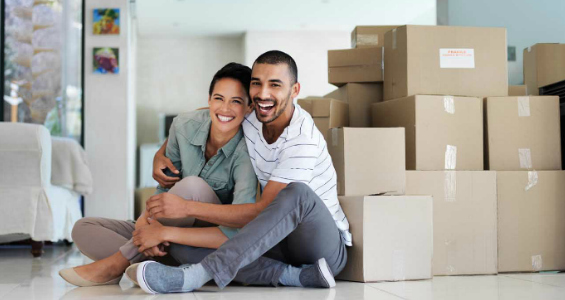 A man and woman sitting happily next to moving boxes