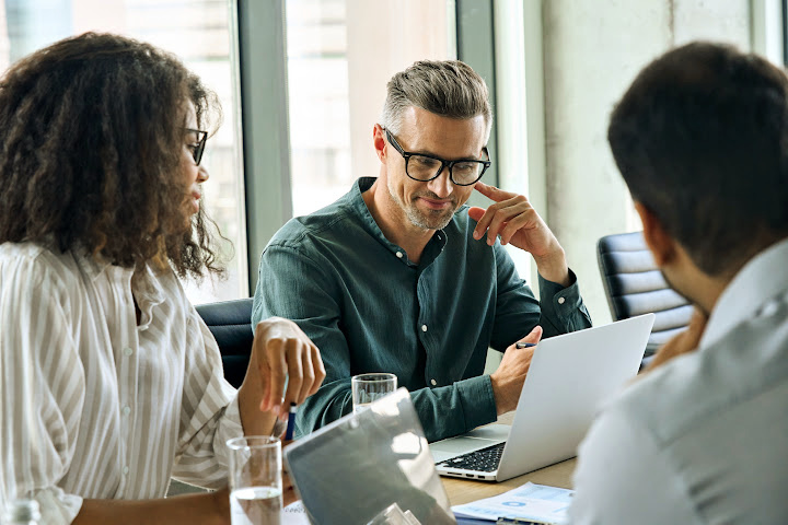 man and woman looking at laptop with man on other side of table