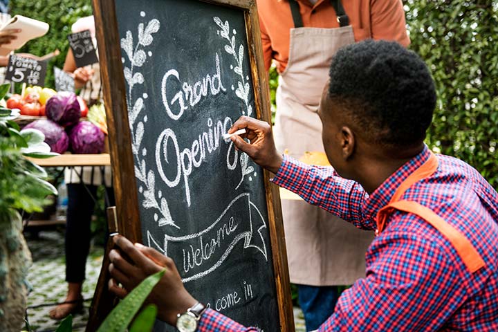 Man writing Grand Opening on chalkboard