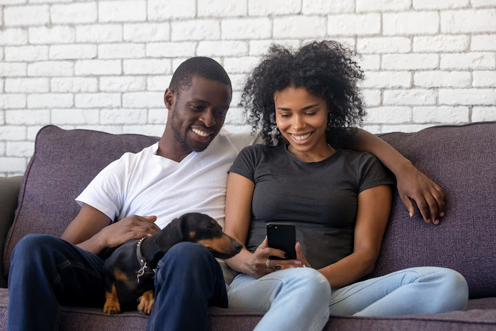 man, woman, wiener dog with woman looking at cell phone