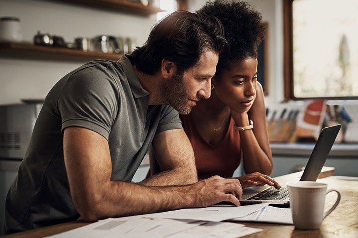 Young couple looking at laptop in kitchen