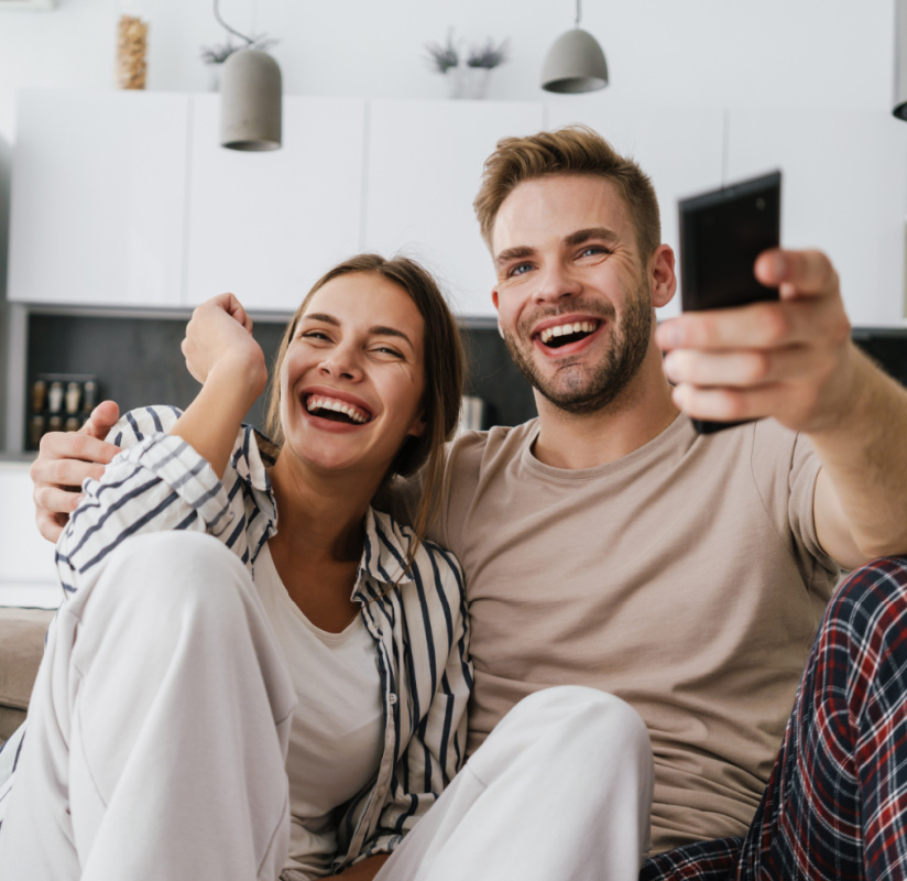 happy man and woman watching TV on a couch