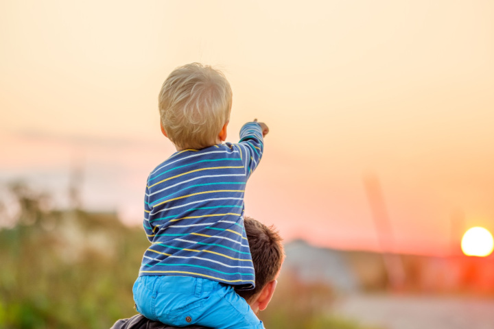 small boy pointing at a sunset