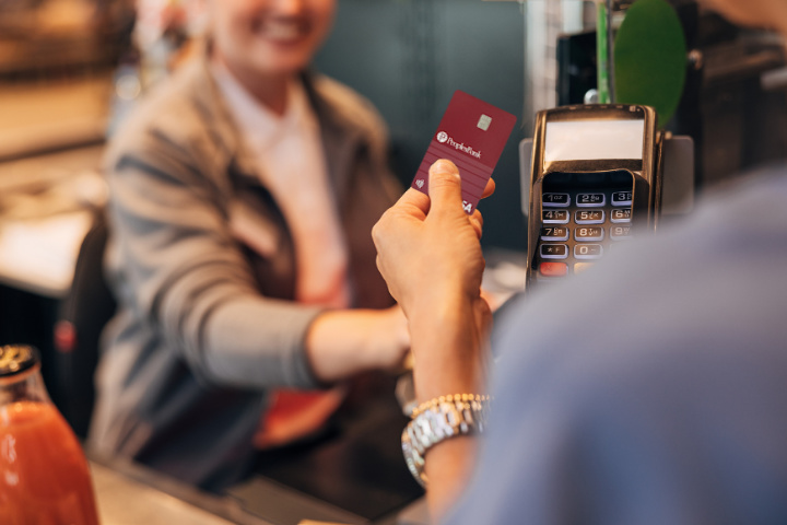 Hand holding Peoples Bank Personal Credit Card at checkout
