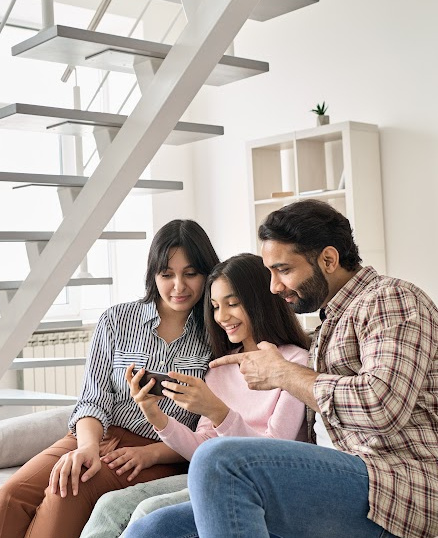 mom, dad, and daughter looking at cell phone