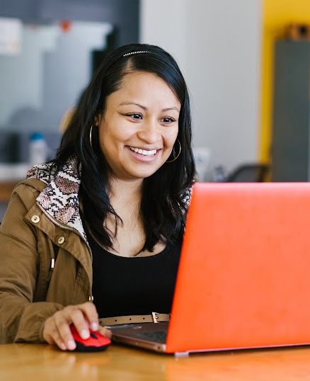 Happy Hispanic woman looking at laptop