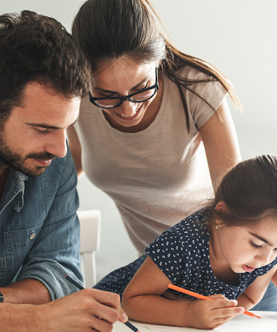 parents helping young daughter write