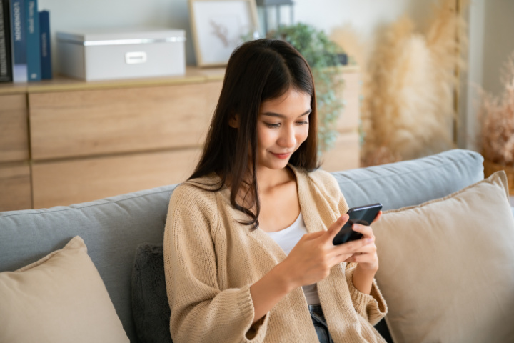 woman looking at cell phone while sitting on a couch