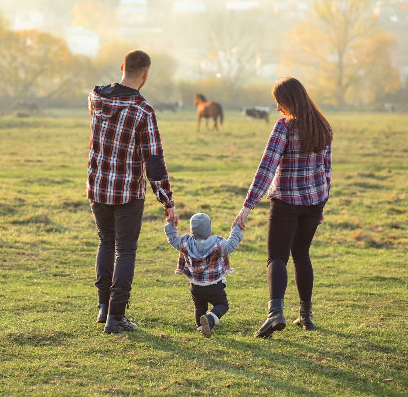 man and woman walking with child near horses