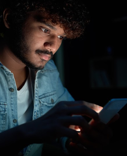 African-American man looking at cell phone in a dark room