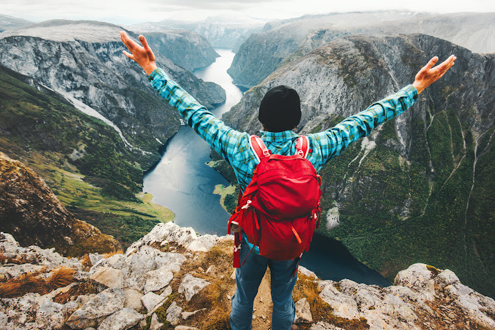 man with arms outstretched on top of mountain