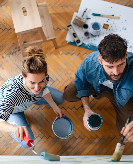 man and woman painting wall in house