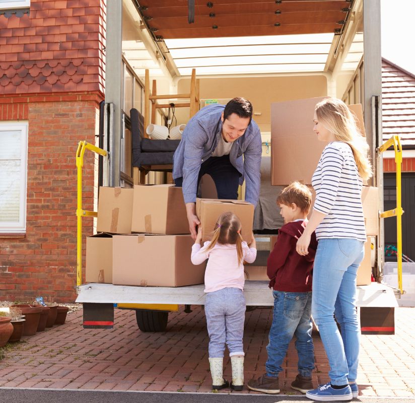 Family unloading moving boxes from truck