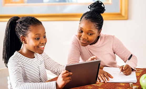 Two young sisters looking at tablet